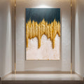 A vertical textured canvas wall art piece featuring a dripping gold pattern over a dark teal top half and cream bottom half, displayed on a light gray wall above a marble ledge.