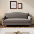 A gray upholstered loveseat sofa with rolled arms and turned wooden legs, shown in a staged living room setting with two framed artworks on the wall above and a small table in the foreground.
