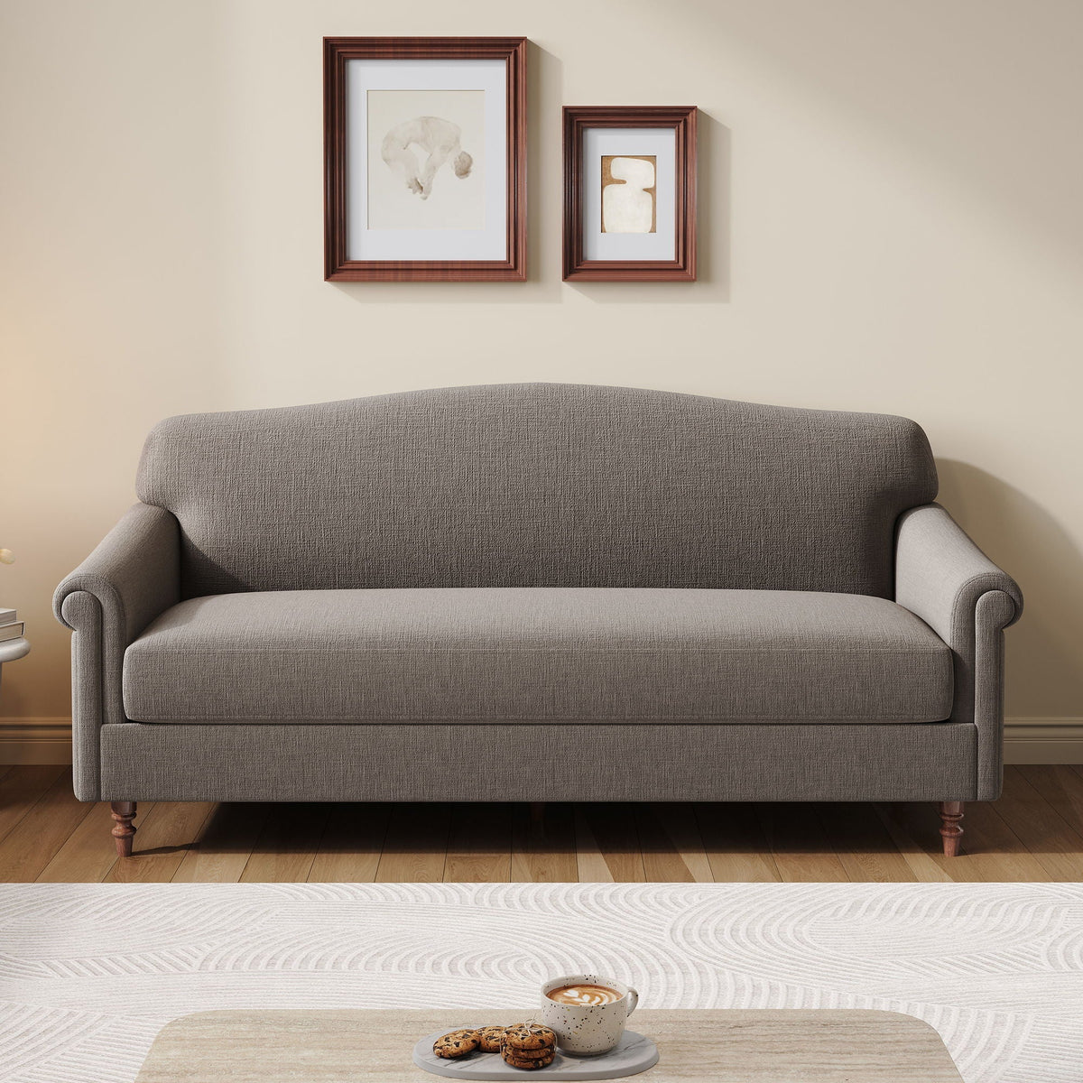 A gray upholstered loveseat sofa with rolled arms and turned wooden legs, shown in a staged living room setting with two framed artworks on the wall above and a small table in the foreground.