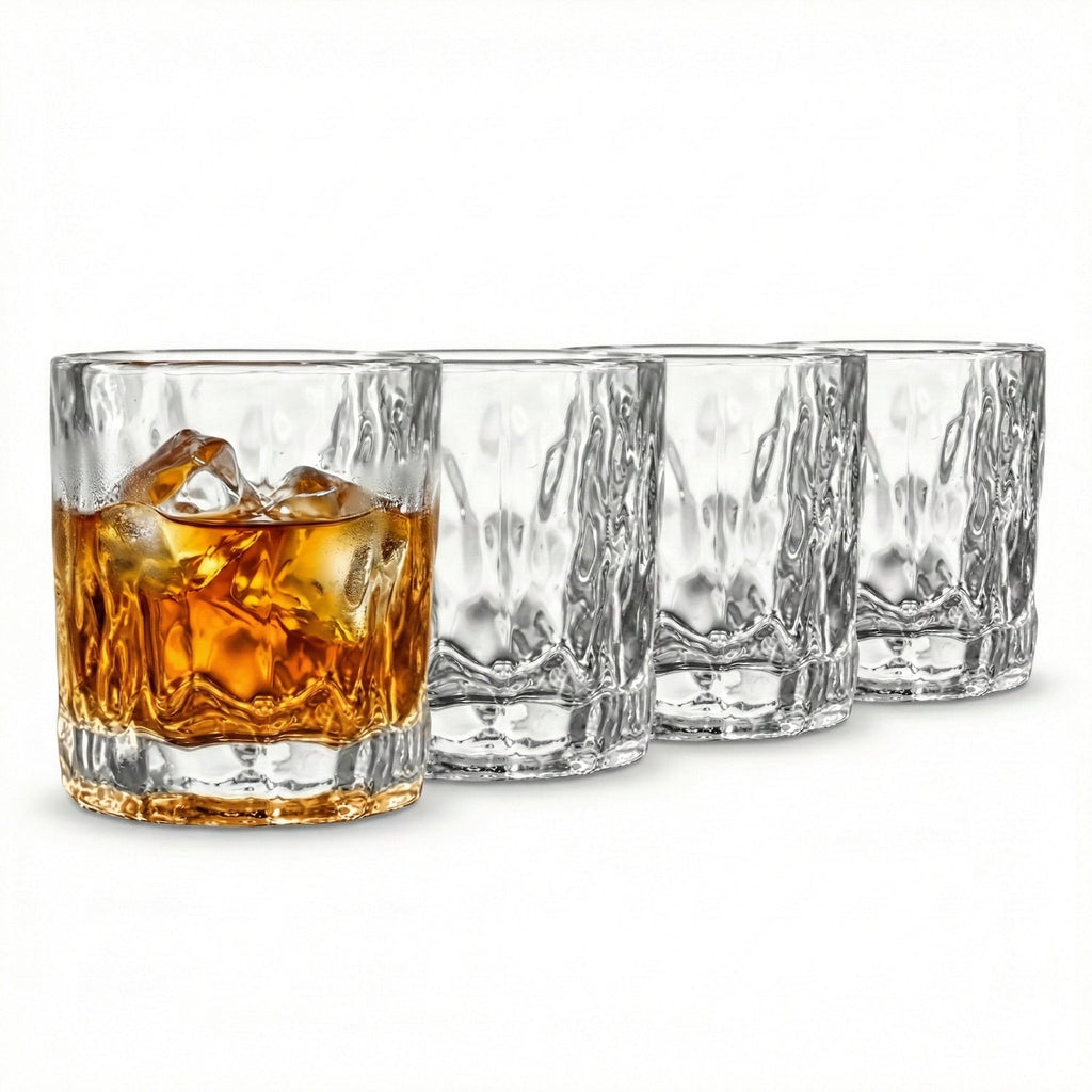 Set of four clear whiskey glasses with one containing a drink and ice cubes on a white background
