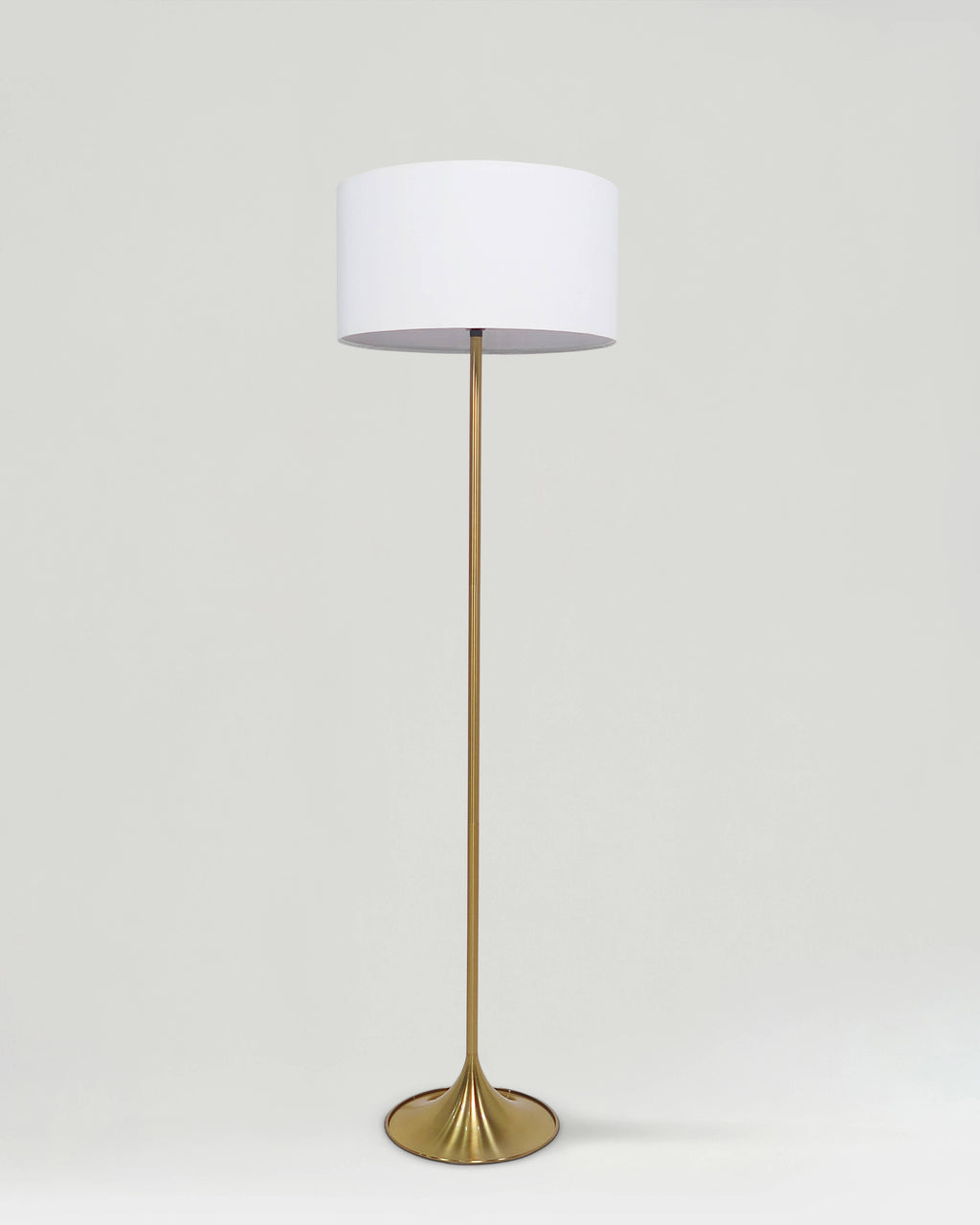 Floor lamp with a white shade and gold base on a light gray background