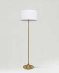 Floor lamp with a white shade and gold base on a light gray background